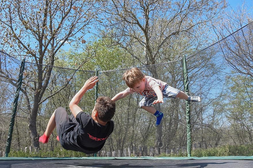 Two boys jumping on a trampoline
