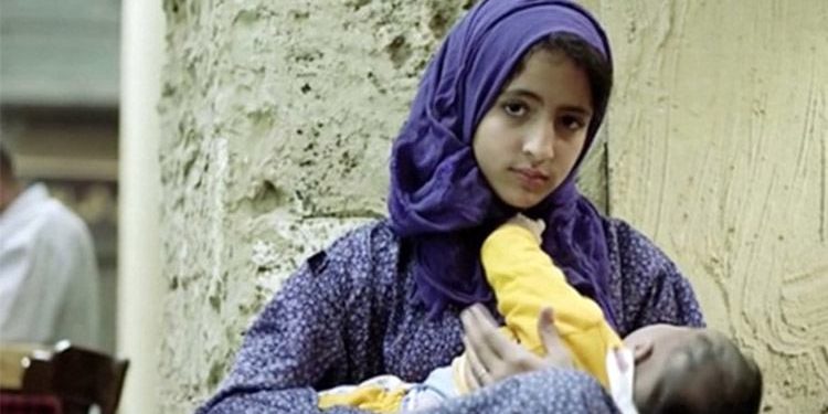 Young teenage Iranian girl holding her baby.