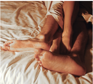 Picture of legs intertwined with bed sheets, representing hooking up.
